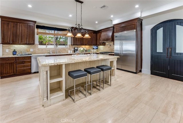 kitchen featuring custom exhaust hood, stainless steel appliances, light stone countertops, a breakfast bar, and a center island