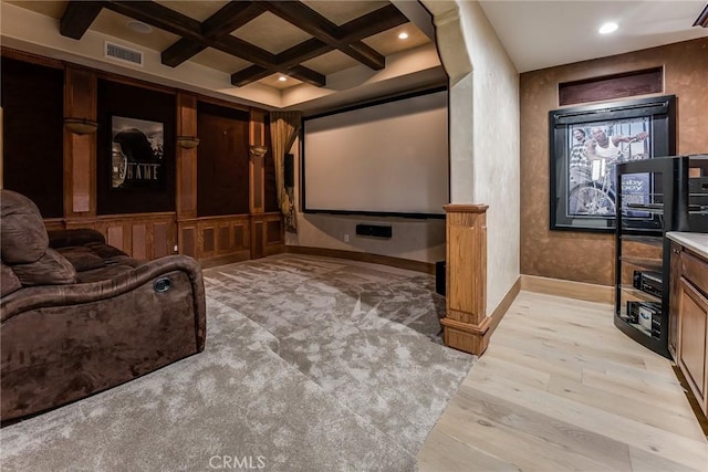 home theater room with light hardwood / wood-style floors, coffered ceiling, and beamed ceiling