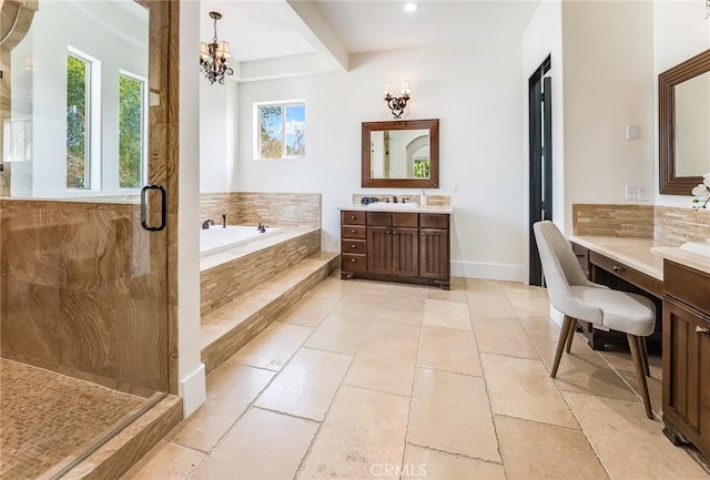 bathroom with tiled bath, vanity, and a notable chandelier