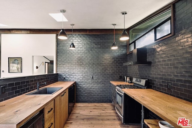 kitchen with decorative light fixtures, stainless steel range with gas cooktop, sink, and butcher block counters