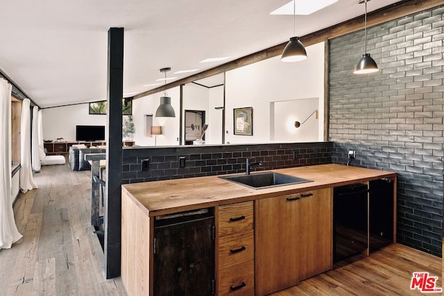 kitchen with wood counters, decorative backsplash, light wood-type flooring, pendant lighting, and sink