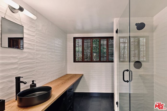 bathroom with sink, tile walls, tile patterned floors, and a shower with door