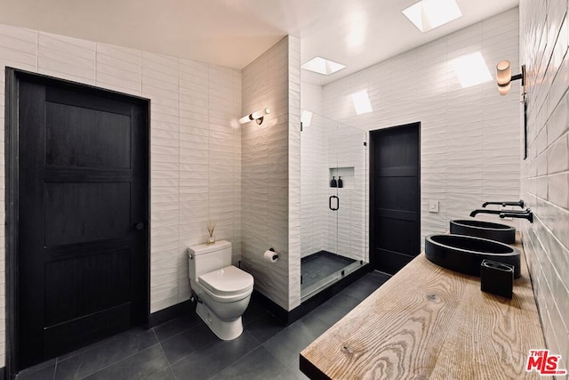 bathroom with walk in shower, toilet, tile walls, tile patterned flooring, and a skylight