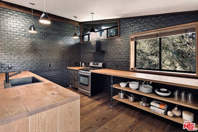 kitchen with pendant lighting, sink, brick wall, stainless steel gas range, and wood counters