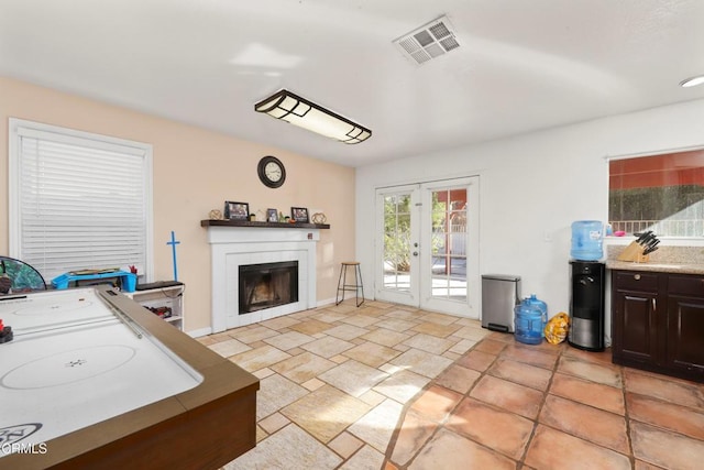 interior space with a tile fireplace and french doors