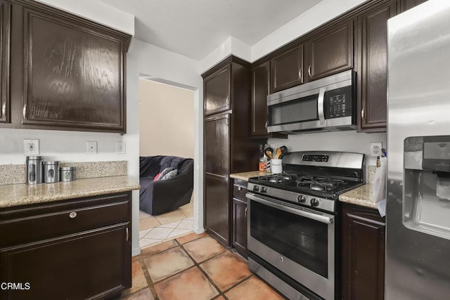 kitchen with appliances with stainless steel finishes, dark brown cabinetry, and light tile patterned flooring