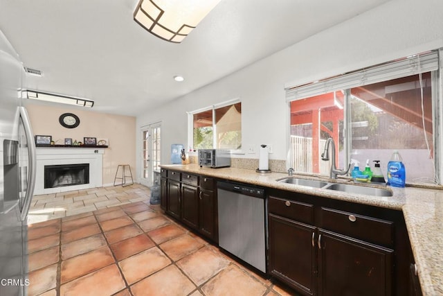 kitchen with light tile patterned flooring, appliances with stainless steel finishes, dark brown cabinetry, and sink