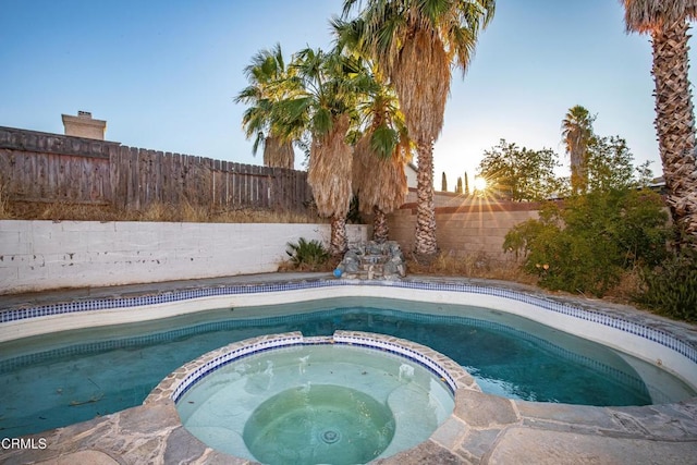 pool at dusk with an in ground hot tub