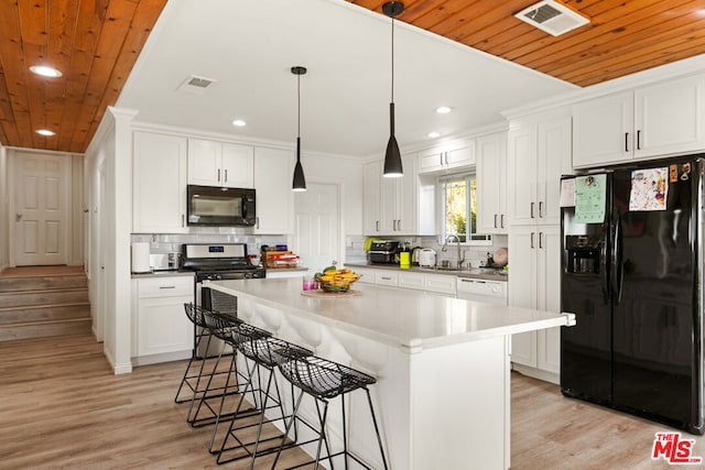 kitchen with a kitchen island, white cabinets, black appliances, and light wood-type flooring