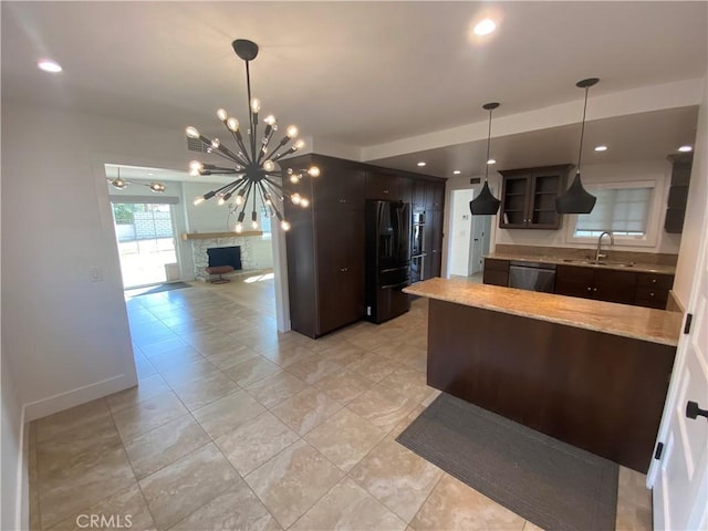 kitchen featuring dark brown cabinetry, black appliances, a fireplace, sink, and a notable chandelier