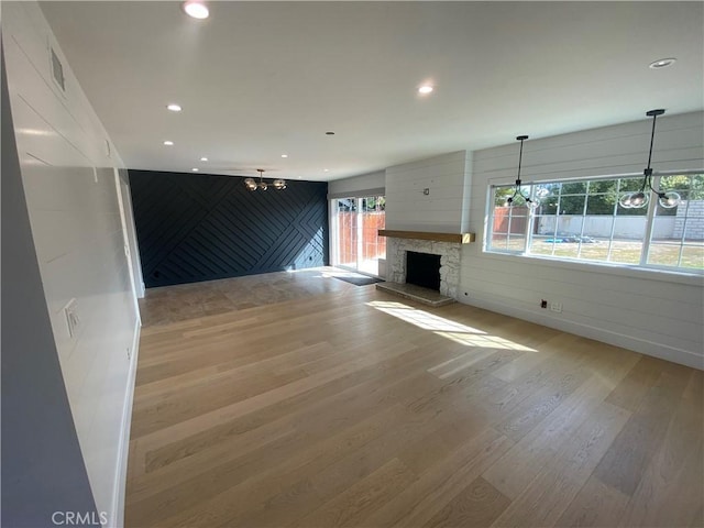 unfurnished living room with light wood-type flooring and a stone fireplace