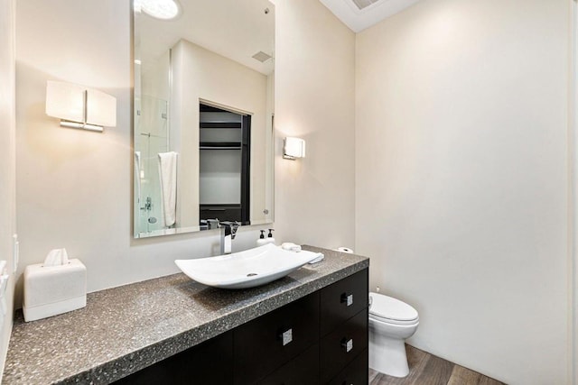 bathroom with vanity, hardwood / wood-style flooring, toilet, and a shower with door