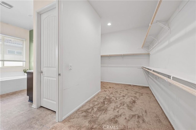 walk in closet with light carpet