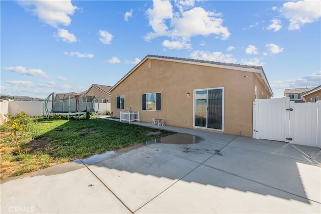 back of property with a trampoline, a patio, a yard, and central air condition unit