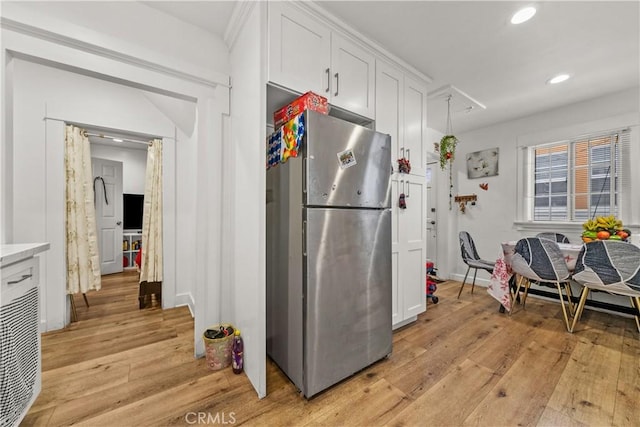 kitchen with white cabinets, stainless steel fridge, and light hardwood / wood-style flooring