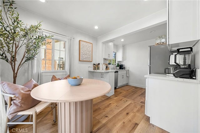 kitchen with kitchen peninsula, white cabinetry, dishwasher, and light wood-type flooring