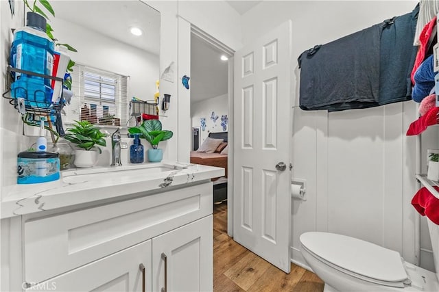 bathroom featuring vanity, wood-type flooring, and toilet