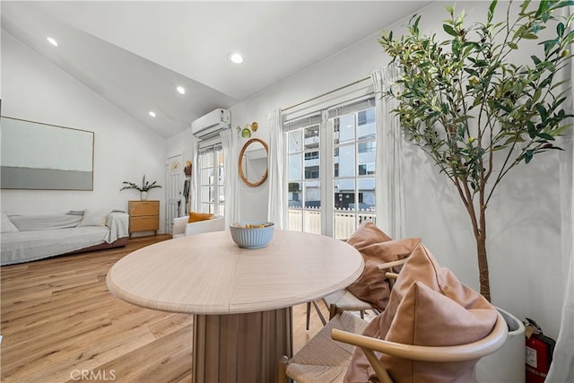 dining room with a wall unit AC, light hardwood / wood-style floors, and lofted ceiling