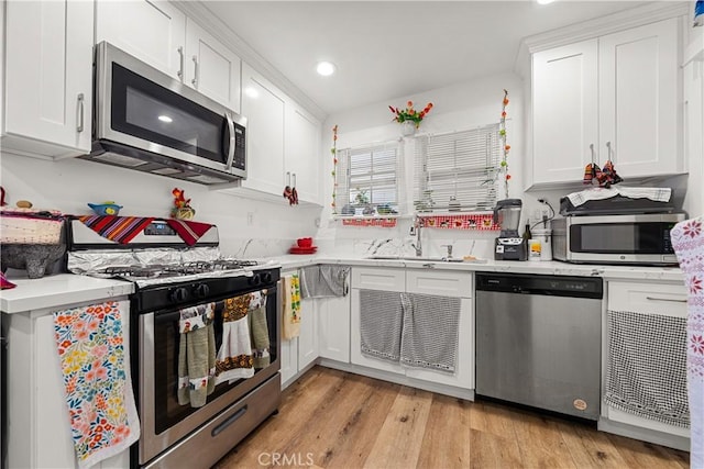 kitchen featuring white cabinets, light wood-type flooring, sink, and appliances with stainless steel finishes