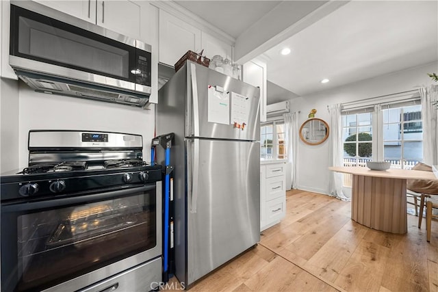 kitchen with stainless steel appliances, beamed ceiling, a wall mounted AC, white cabinets, and light wood-type flooring