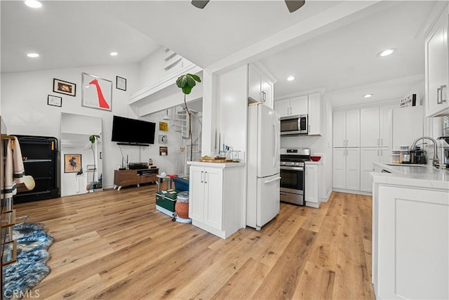 kitchen featuring white cabinetry, sink, high vaulted ceiling, appliances with stainless steel finishes, and light wood-type flooring