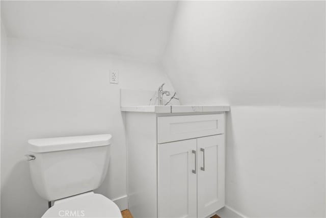 bathroom featuring vanity, toilet, and vaulted ceiling