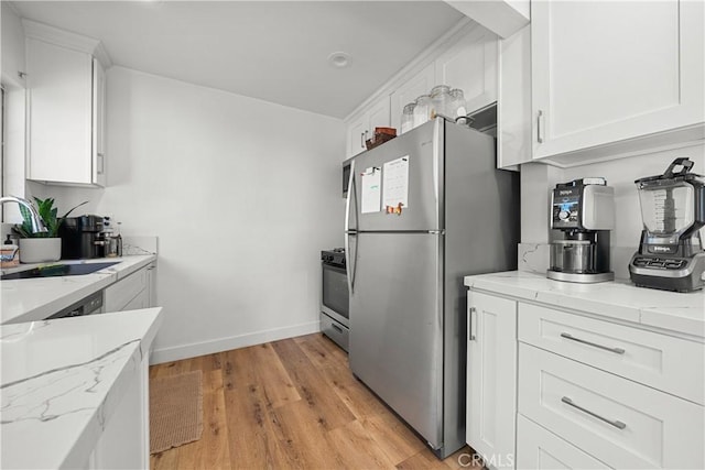 kitchen with appliances with stainless steel finishes, light stone counters, sink, light hardwood / wood-style floors, and white cabinetry