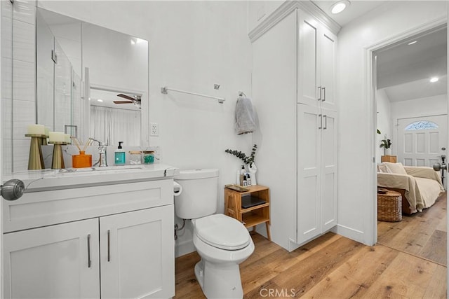 bathroom featuring hardwood / wood-style flooring, ceiling fan, toilet, and vanity