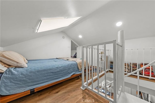 bedroom with hardwood / wood-style flooring and vaulted ceiling with skylight