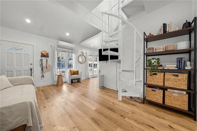 bedroom with a wall mounted air conditioner, light hardwood / wood-style floors, lofted ceiling, and french doors