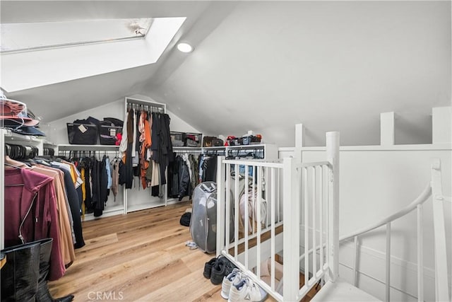 spacious closet featuring vaulted ceiling with skylight and hardwood / wood-style floors