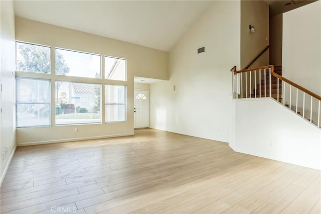 unfurnished living room featuring high vaulted ceiling and light hardwood / wood-style flooring