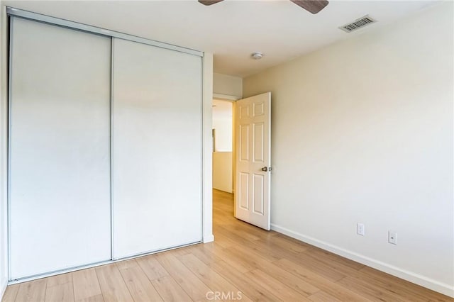 unfurnished bedroom with ceiling fan, a closet, and light wood-type flooring