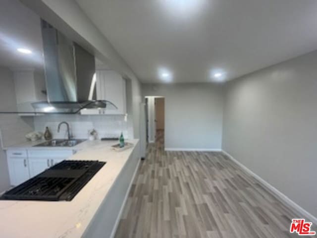 kitchen featuring white cabinetry, sink, tasteful backsplash, black gas cooktop, and light hardwood / wood-style floors