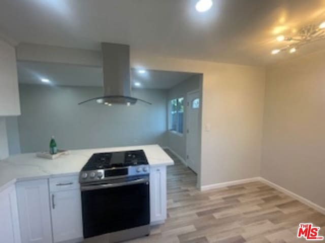 kitchen featuring white cabinetry, light hardwood / wood-style floors, stainless steel range oven, kitchen peninsula, and island exhaust hood