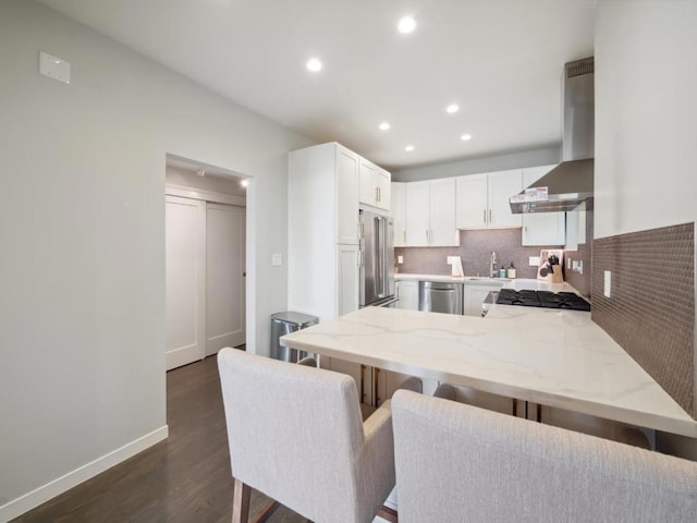 kitchen featuring a breakfast bar, white cabinetry, appliances with stainless steel finishes, island range hood, and kitchen peninsula