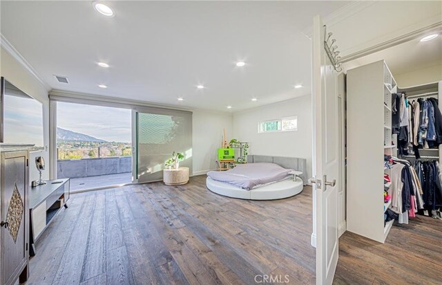 bedroom featuring wood-type flooring, ornamental molding, and a closet