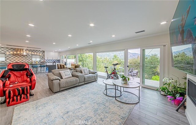 living room with crown molding and light hardwood / wood-style floors