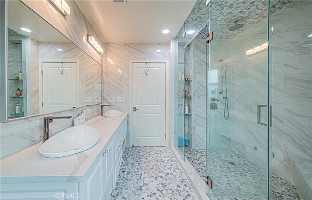 bathroom with an enclosed shower, vanity, and tile walls