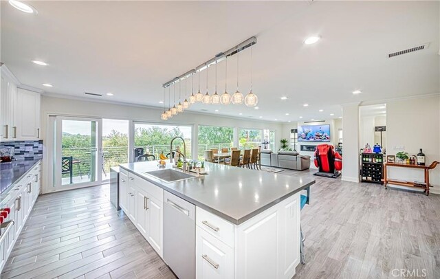 kitchen featuring white cabinetry, dishwasher, sink, an island with sink, and decorative light fixtures