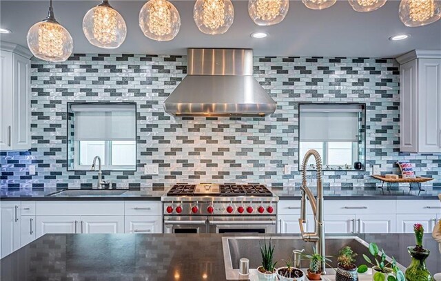 kitchen with sink, wall chimney range hood, tasteful backsplash, pendant lighting, and double oven range