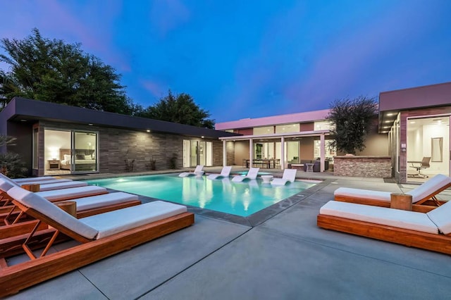 pool at dusk with a patio area