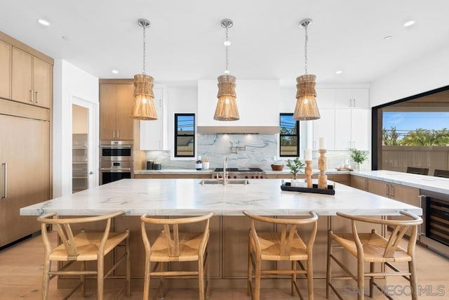 kitchen featuring a wealth of natural light, a large island, light brown cabinetry, and paneled fridge