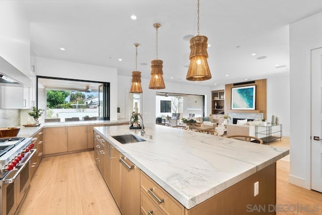 kitchen featuring a spacious island, sink, double oven range, light hardwood / wood-style floors, and hanging light fixtures