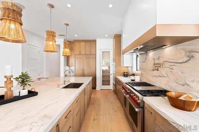 kitchen featuring sink, hanging light fixtures, light hardwood / wood-style flooring, high quality appliances, and custom range hood