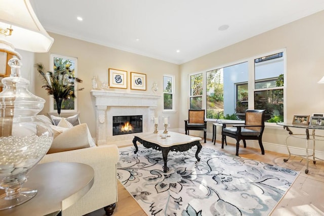 living room featuring light wood-type flooring, a premium fireplace, and crown molding