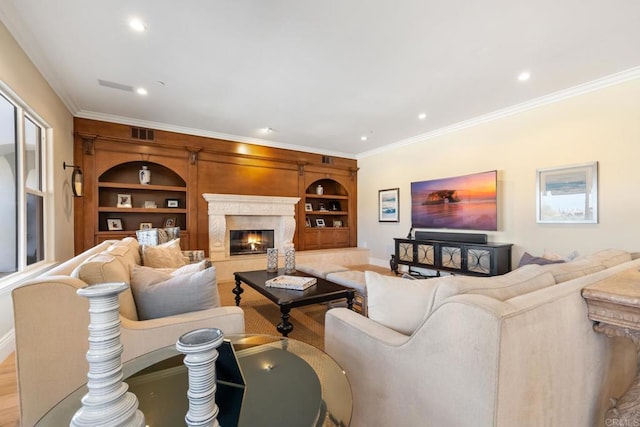 living room with a high end fireplace, built in features, crown molding, and light hardwood / wood-style flooring