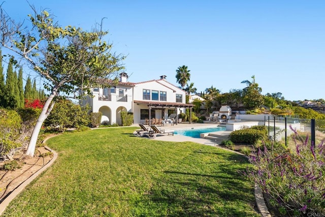 rear view of house featuring a lawn, a balcony, and a patio