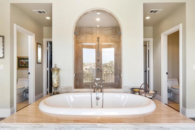 bathroom featuring toilet, tiled bath, and french doors