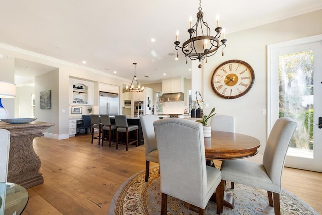 dining area with a notable chandelier, ornamental molding, and light hardwood / wood-style floors